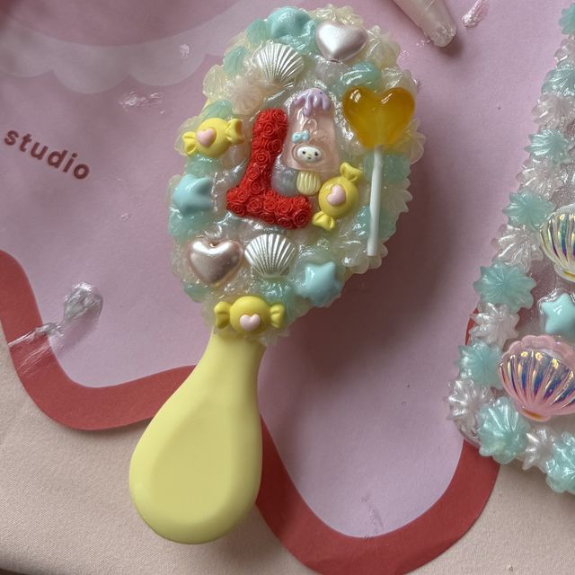 A decoden hair brush with mint cream, shells and a monogram letter