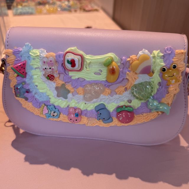 A finished lilac decoden handbag covered in pastel cream and charms